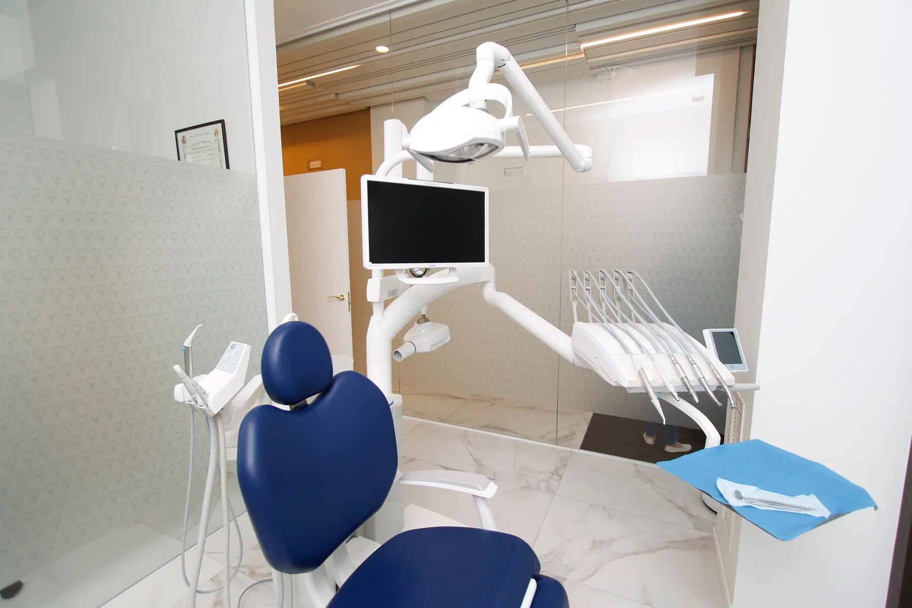 Gabinete de la clínica con sillón dental azul y pantalla digital