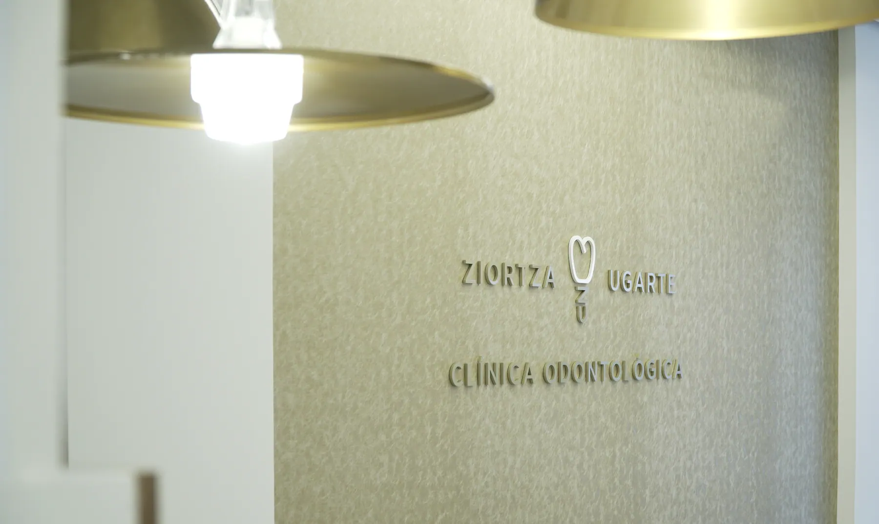 Pared con el logotipo de Ziortza Ugarte y lámpara dorada